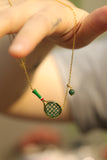 Women’s tennis racket necklace styled with a green sports outfit